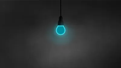 A single cyan bulb hangs from a cord at top centre, its glow fading into a plain dark grey wall that leaves the lower half free for icons.