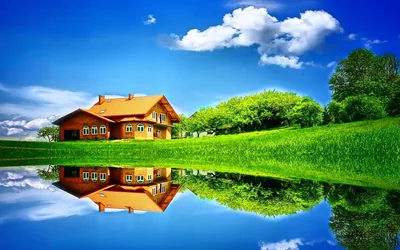 A red-roofed cottage sits just left of centre, doubled exactly in the pond below; the heavy saturation gives this composite a picture-book look on large monitors.