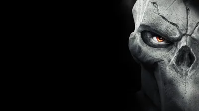 A cracked bone mask fills the right edge in close-up, one orange eye burning inside the socket, the left half of the frame empty black.