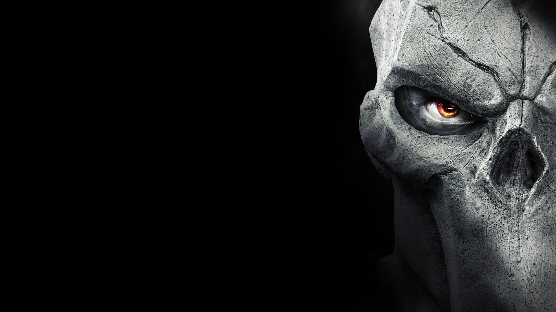 A cracked bone mask fills the right edge in close-up, one orange eye burning inside the socket, the left half of the frame empty black.
