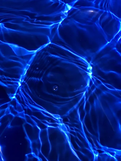 Electric caustic lines web across near-black pool water like neon threads, densest through the upper half and loosening toward the bottom where icons read cleanly.