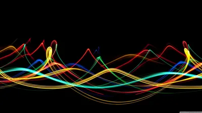 Long-exposure light trails in red, yellow and green ripple across the middle of a black frame, peaking into small loops.