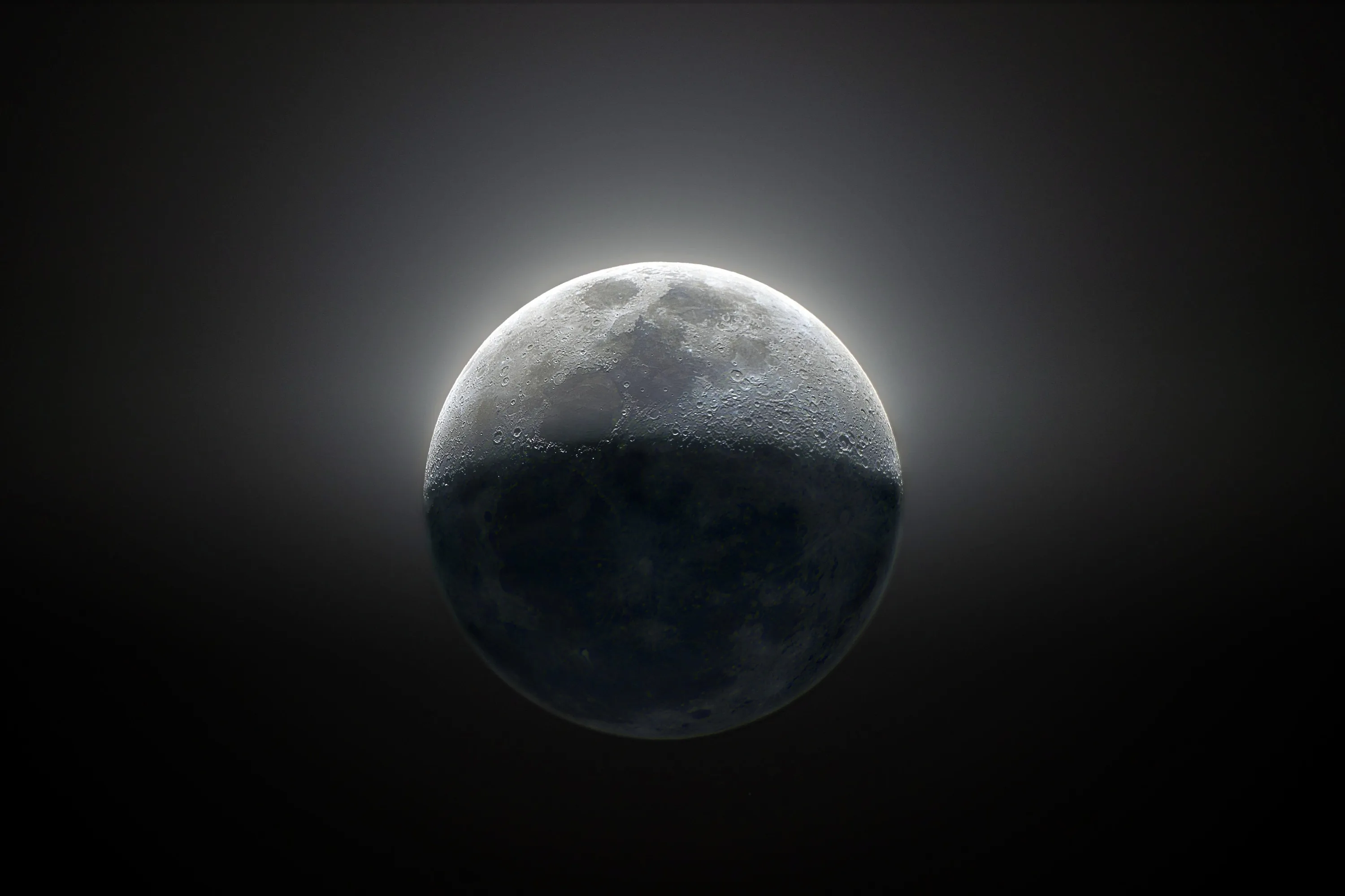 Light blazes along the moon's upper rim while its lower half sinks into shadow, the rest of the frame flat black for OLED screens.
