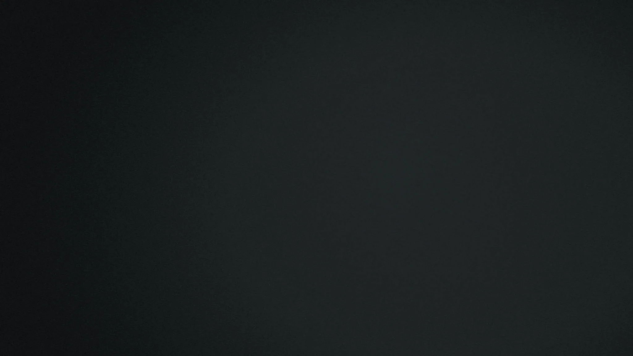 An almost featureless charcoal field with a slightly lighter patch left of centre, smooth enough to sit behind icons anywhere on screen.