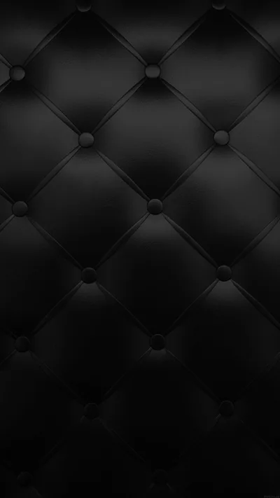 Buttoned black leather in a diamond tuft, each seam pulling the surface into soft folds under a low even light.