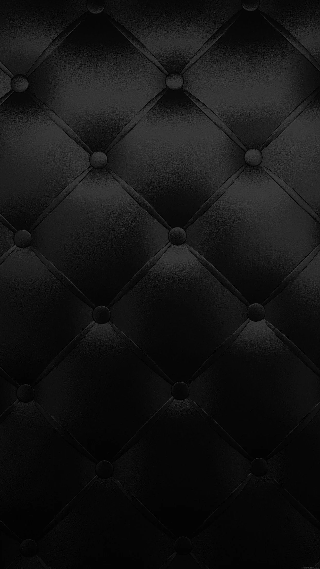 Buttoned black leather in a diamond tuft, each seam pulling the surface into soft folds under a low even light.