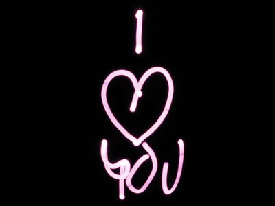 A pink neon tube spells I love you in loose handwriting, the heart standing in for the word love, everything else pure black.