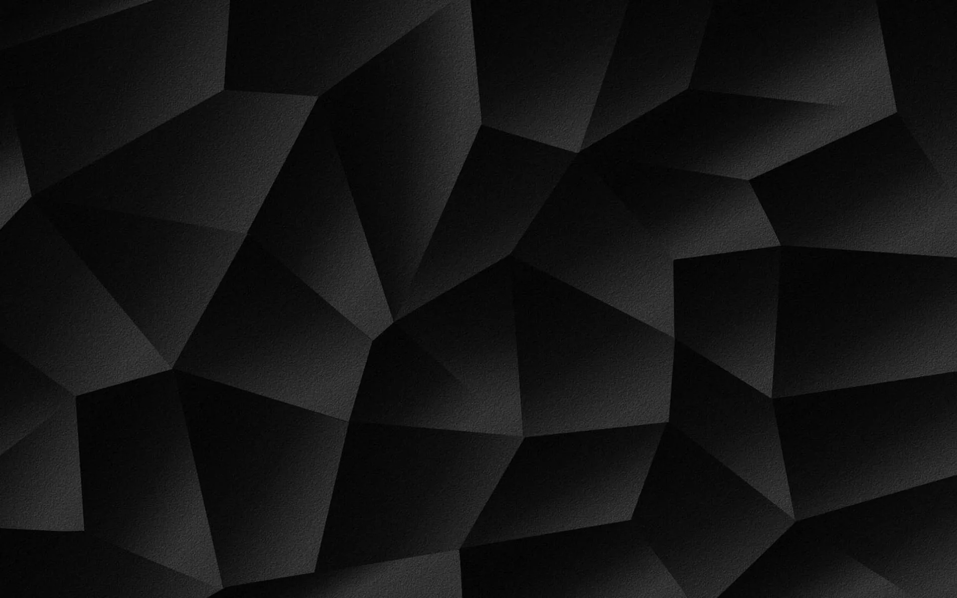 Large flat facets tilt at different angles across the frame, each one a slightly different grey, with the brightest edge running through the upper left.