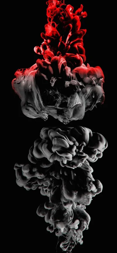 Red ink billows above its own grey mirror image, both suspended in black water with the plume tapering down to a thin stem.