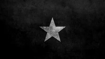 A weathered five-pointed star sits centred on a scratched dark grey wall, the texture heaviest around the corners.