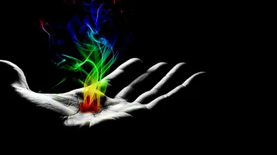 A greyscale open palm enters from the lower right holding a small flame, rainbow smoke curling toward the top edge, everything else pure black for OLED screens.
