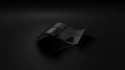 The Windows mark rendered as a shiny black object resting on a dark floor, one edge catching the light.