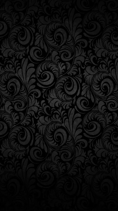 A repeating baroque swirl pattern in charcoal on black, the raised curls catching just enough light to separate from the background.