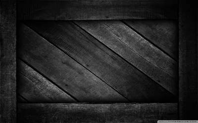 Rough boards laid at a diagonal inside a grey frame, the grain and old nail marks picked out by a dim light from above.