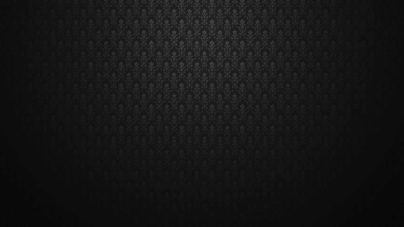 A tight fleur-de-lis print embossed on near-black fabric, centre lit and the outer frame dropping into shadow.