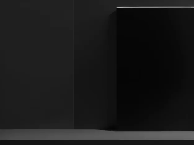A glossy black panel stands against a matte grey wall with a thin strip of light along its top edge, casting a soft shadow onto the shelf below.