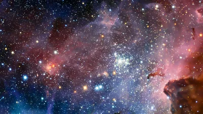 A Hubble-style view into the Carina Nebula, thousands of stars packed around a bright central cluster with pink gas glowing at the edges.