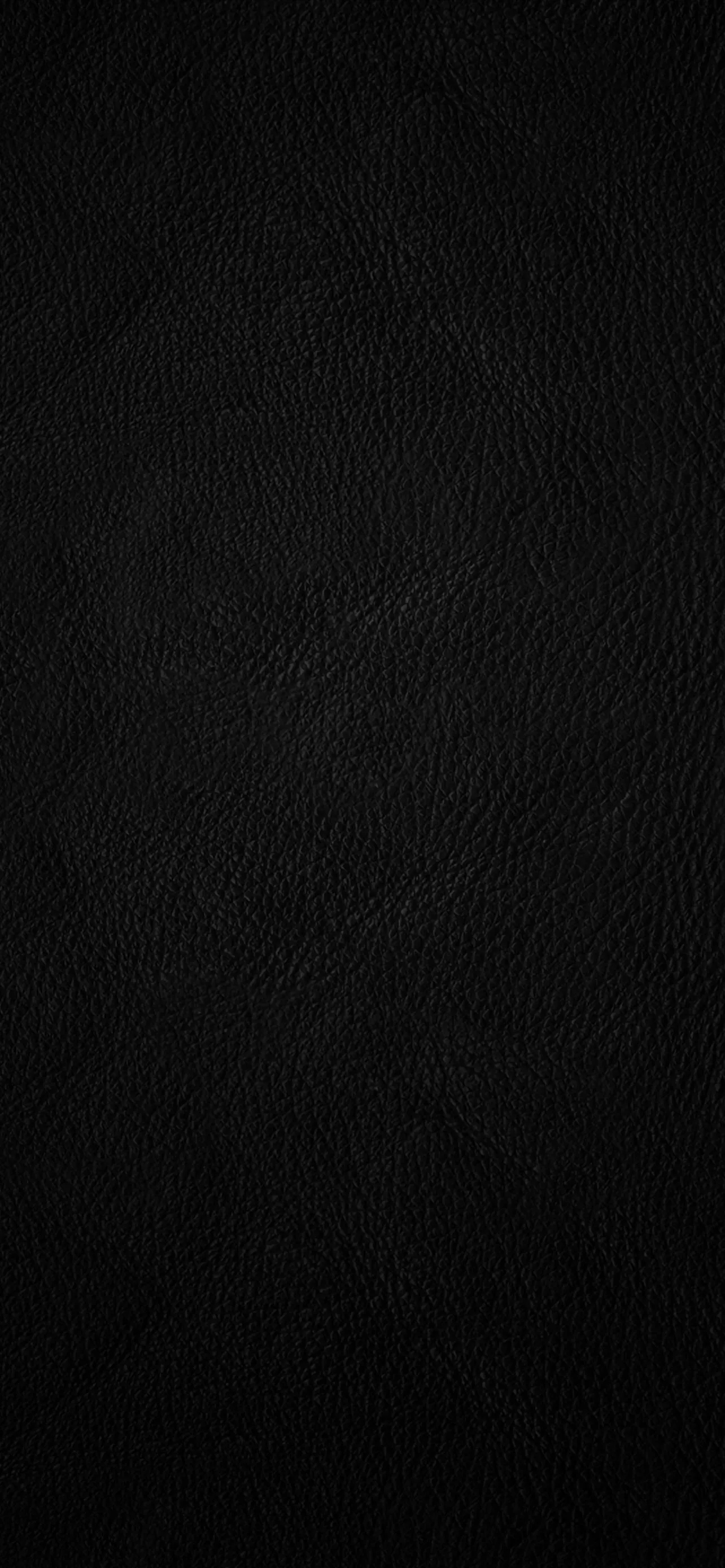 Fine pebbled grain runs down a tall near-black surface, a soft sheen along the left edge and the bottom third left almost featureless.