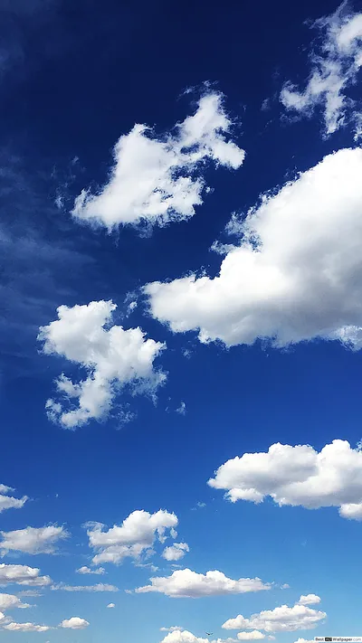 Puffy white cumulus drifts up the right side of a deep saturated blue sky, leaving the upper left mostly empty for a status bar.