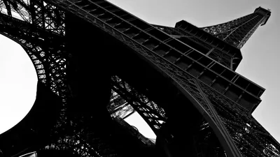 The tower is shot looking straight up in hard black and white, its ironwork filling the right side of the frame.