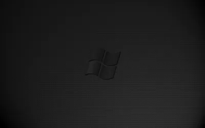 The Windows emblem pressed into a faintly ridged charcoal surface, catching just enough light at its edges to read as metal.