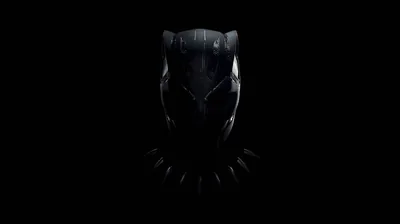 The mask emerges from near-total darkness, only the ridge of the ears and the cheekbones catching light.
