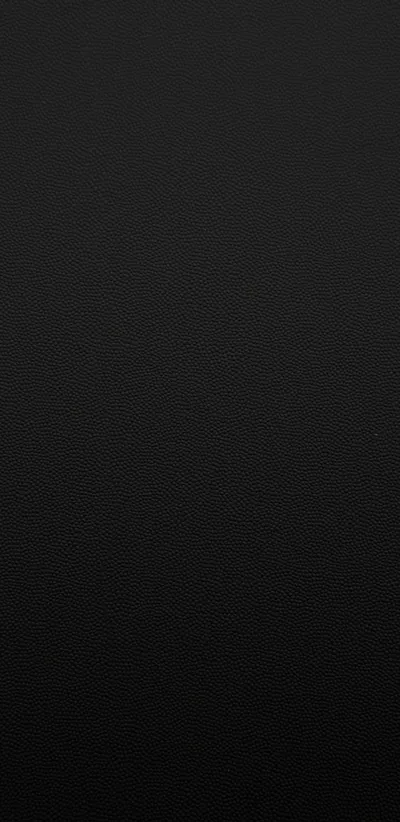 A fine leather-like grain runs edge to edge, the top corner a shade lighter than the rest before the whole frame settles into flat black.