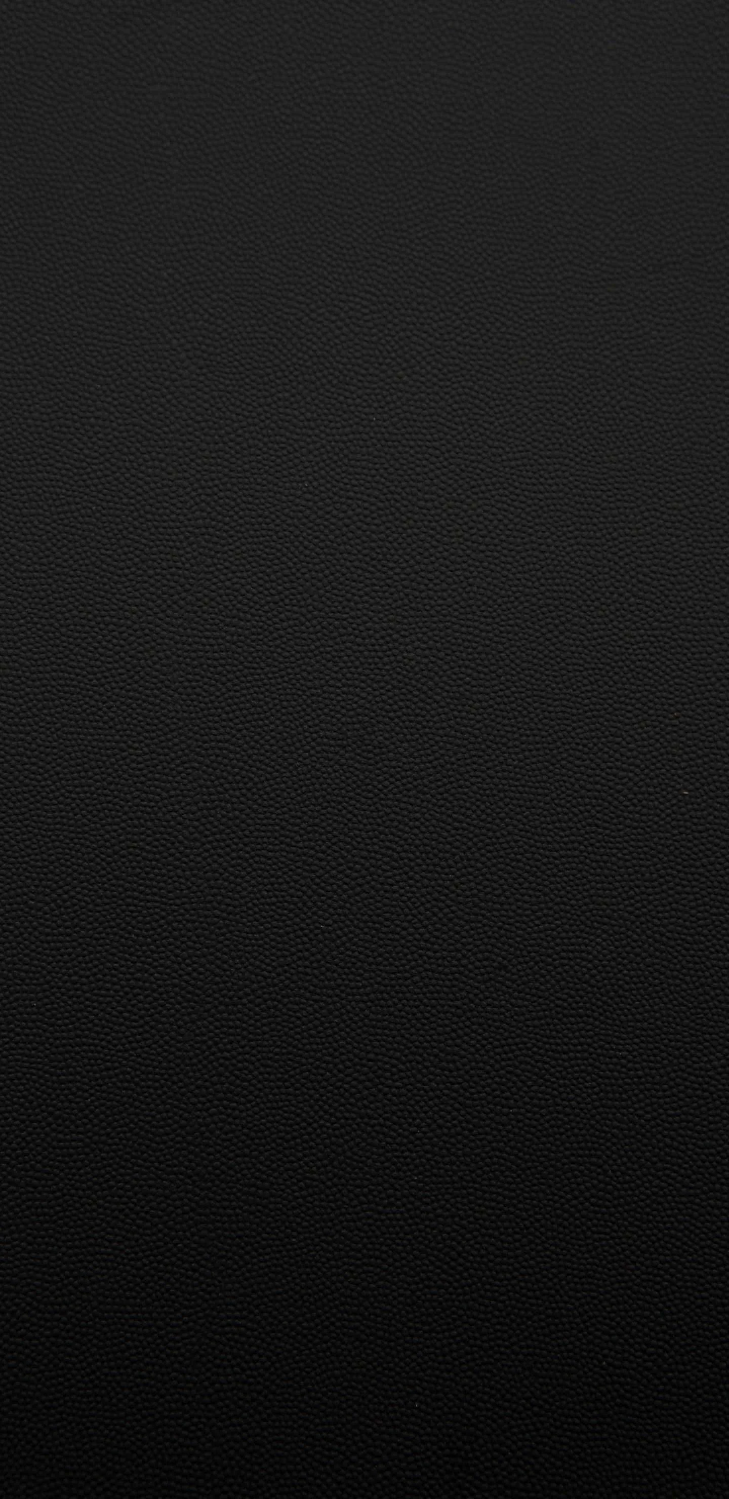 A fine leather-like grain runs edge to edge, the top corner a shade lighter than the rest before the whole frame settles into flat black.