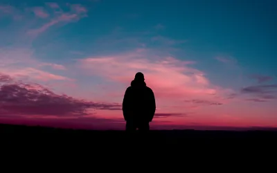 Magenta clouds streak the blue evening sky behind a standing figure, and the unlit foreground leaves a flat black base for a dock or icons.