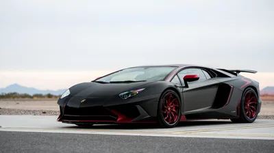 Satin black bodywork against pale desert scrub, crimson rims and side blades the only colour with low hills sitting flat on the horizon.
