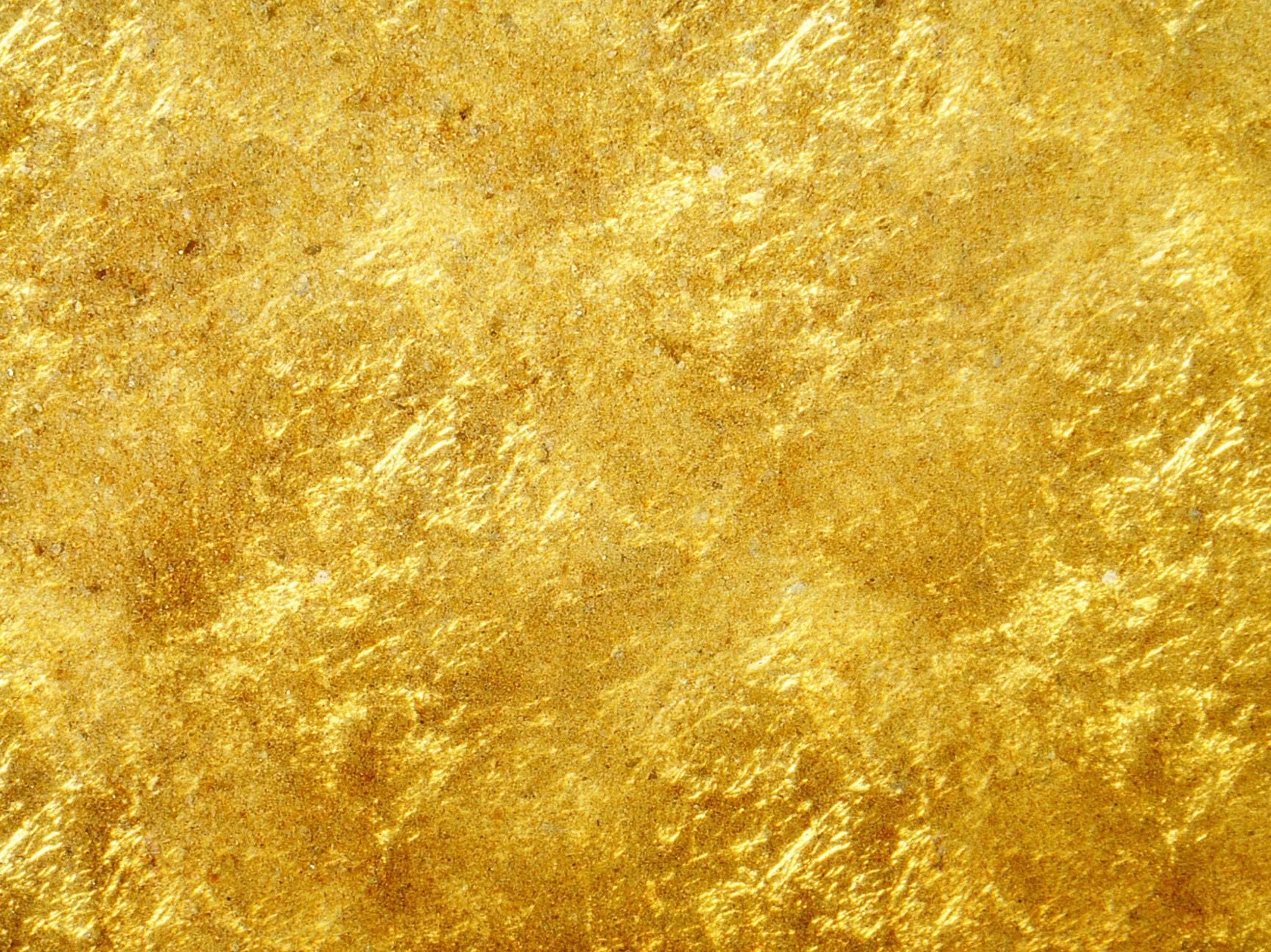 Beaten gold foil in a full-frame close-up, its dents and darker specks spread evenly so the texture holds up behind desktop icons.