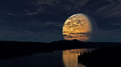A moon streaked with sunset-coloured cloud shadows sets behind black hills, a river below catching only a faint strip of its light.
