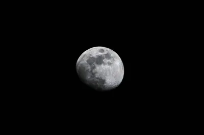 A telephoto waxing gibbous moon centred on unbroken black, craters sharpening along the terminator — plain sky on every side keeps desktop icons legible.