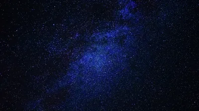 The galaxy's core glows blue at centre-right, thinning to near-black edges — most of the frame stays dark enough for battery-friendly phone screens.