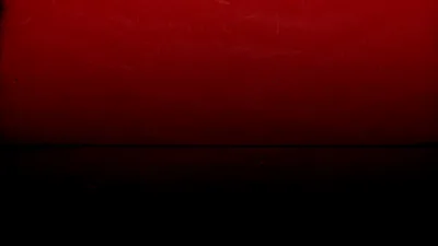 A wash of red covers the upper half and blurs into solid black below, faint scratches showing where the light catches the surface.