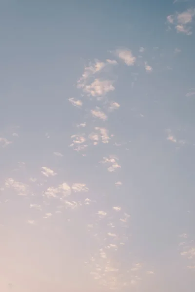 A pale evening sky of tiny broken clouds, blue above fading to warm peach below — quiet enough that white lock-screen text reads anywhere.
