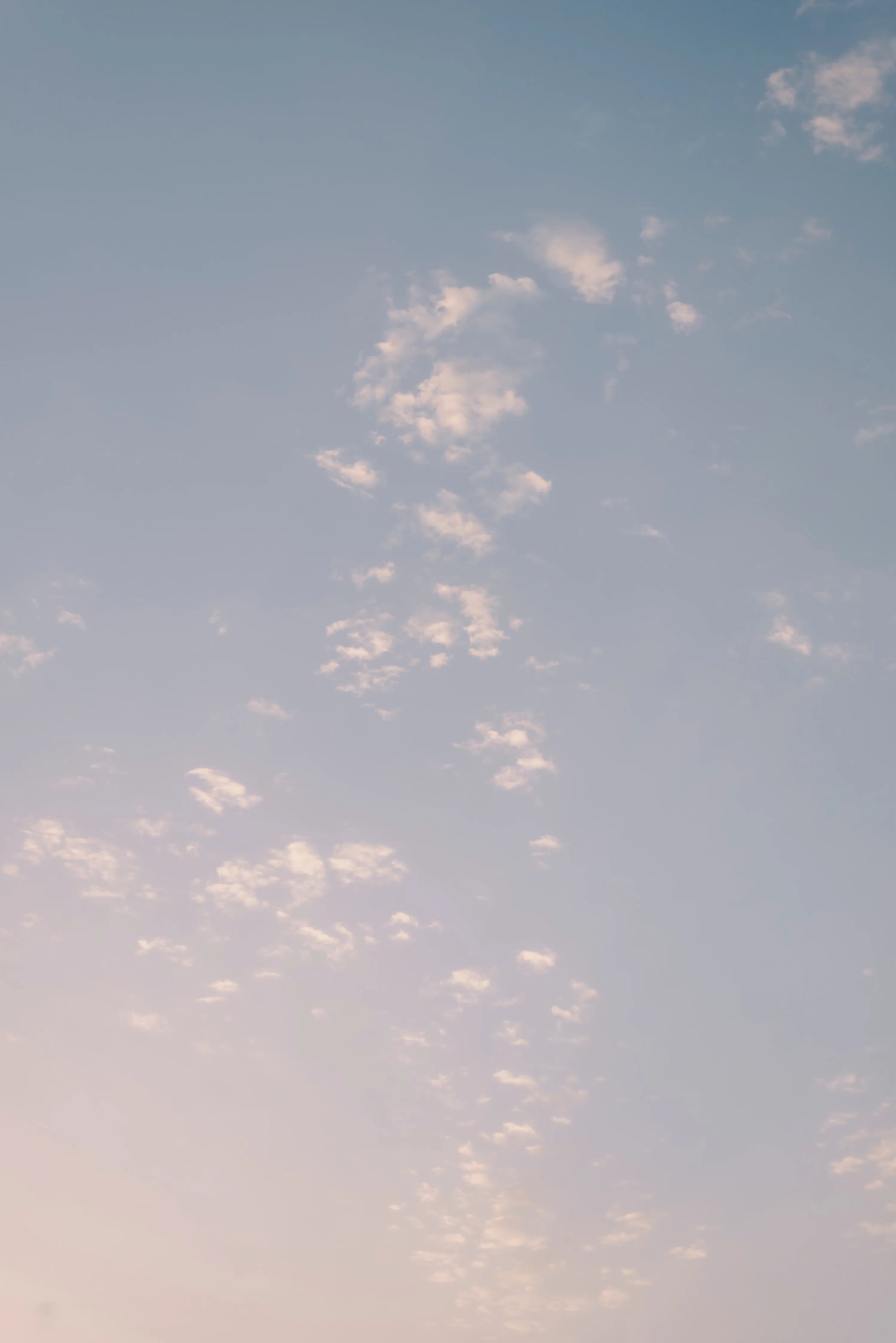 A pale evening sky of tiny broken clouds, blue above fading to warm peach below — quiet enough that white lock-screen text reads anywhere.