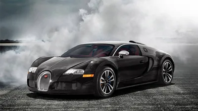 The Veyron sits front-quarter on with white smoke boiling across the ground behind it, chrome grille and door blade catching the low grey light.