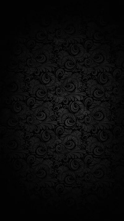 A repeating damask print on dark wallpaper, lit faintly in the middle so the edges and all four corners fall away into black.
