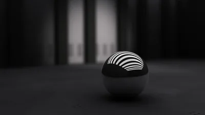 A glossy ball banded in black and white curves sits on a bare dark floor, the blurred columns behind it dissolving into grey.