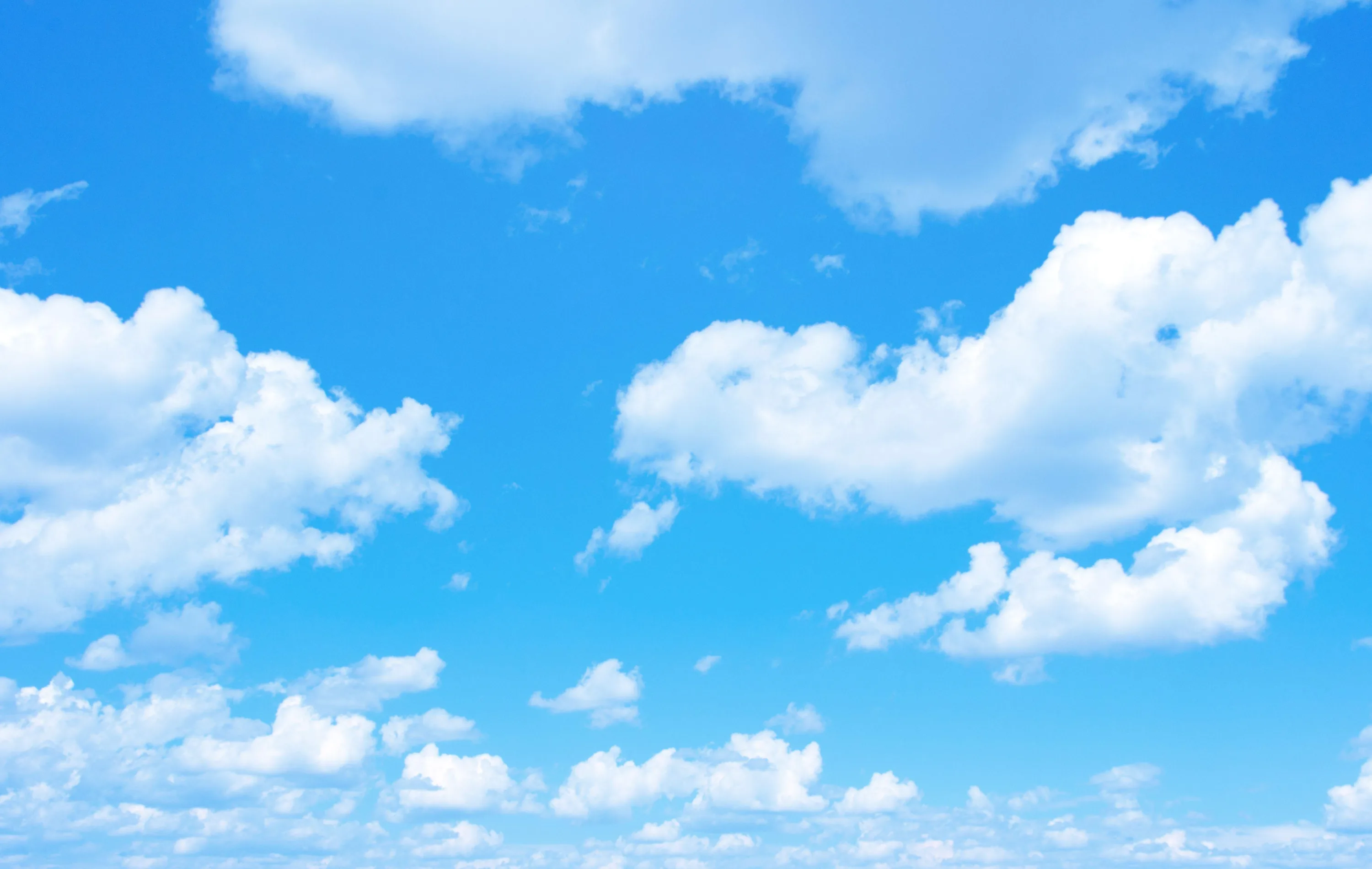 Fair-weather cumulus scattered across a saturated blue sky — nothing but cloud and blue, a clean backdrop that keeps every desktop icon visible.