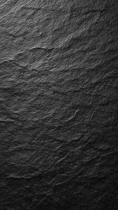 A slab of dark slate raked by light from the upper left, every flake and chip in the stone throwing its own small shadow.