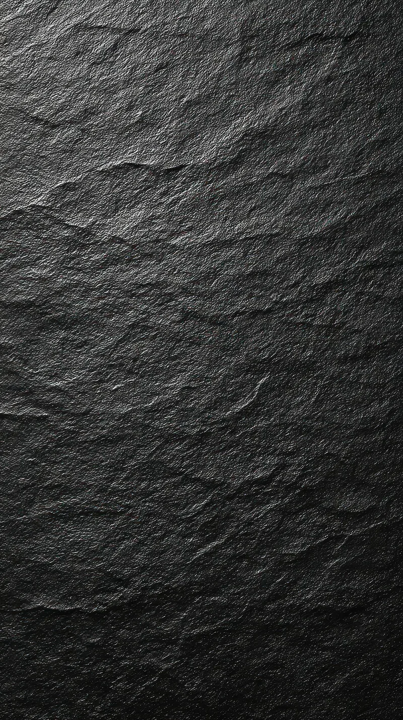 A slab of dark slate raked by light from the upper left, every flake and chip in the stone throwing its own small shadow.