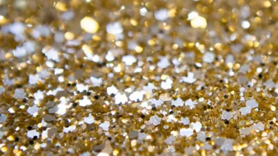 A macro spill of mixed gold and silver flecks, sharp through the middle and melting into soft bokeh along the top edge.