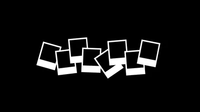 A loose row of blank white instant-photo frames leans across the middle of the frame, everything above and below flat black.