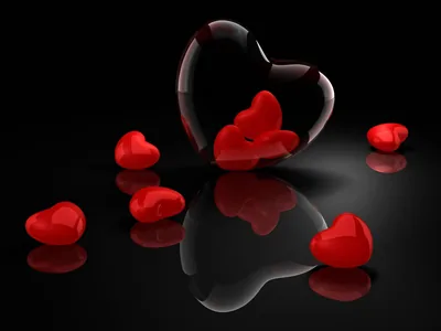 Glossy red hearts sit on a black mirrored surface, one outlined in glass at the centre.