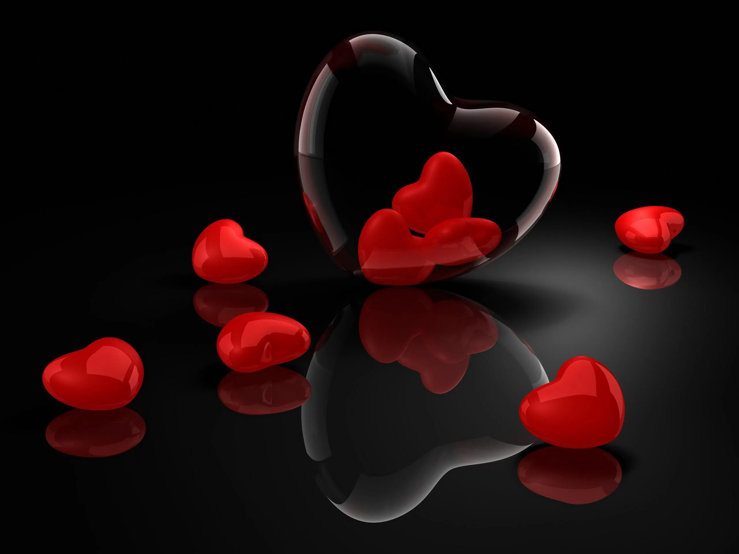 Glossy red hearts sit on a black mirrored surface, one outlined in glass at the centre.