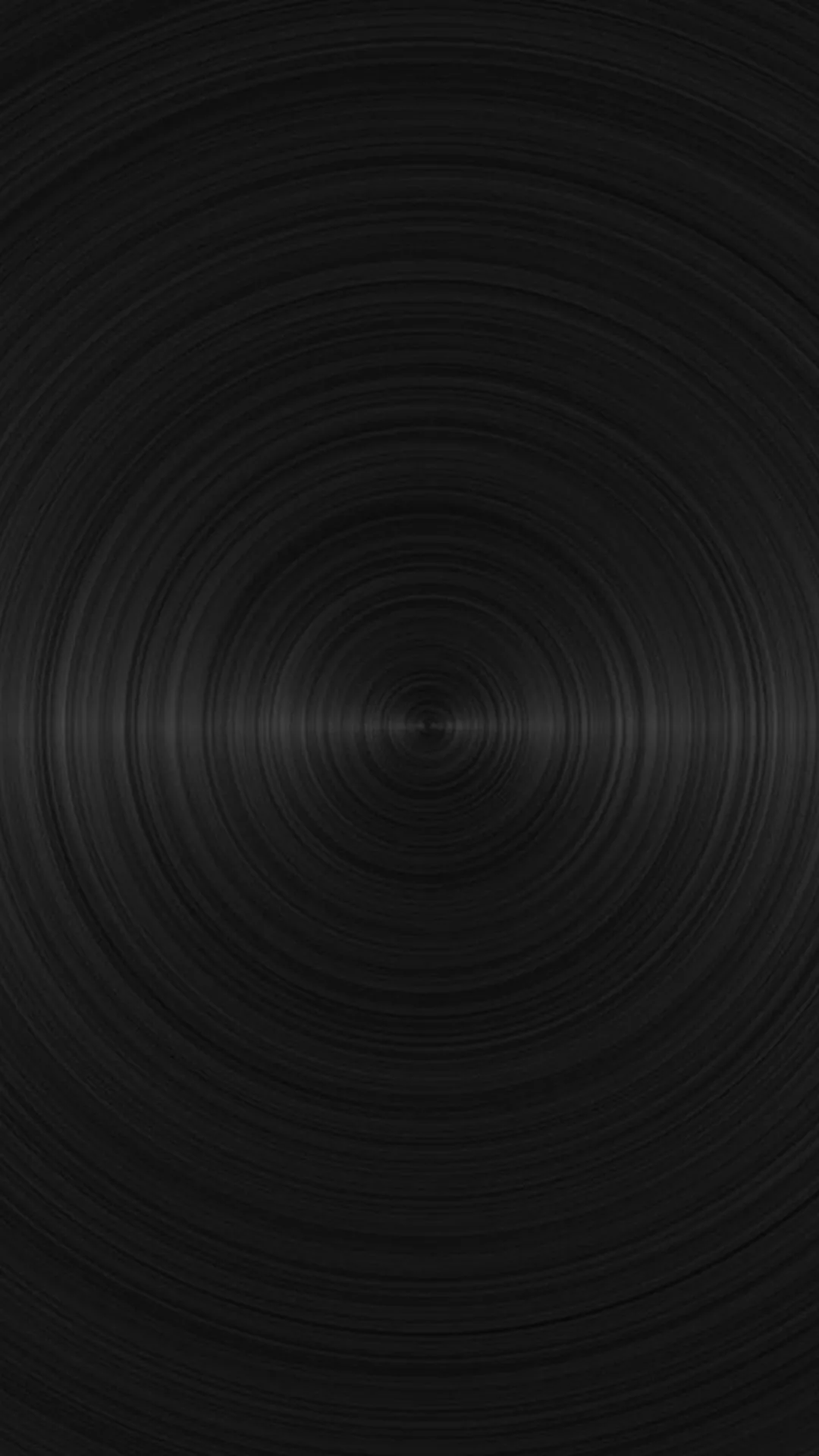 Rings of brushed metal spin out from a point just below centre, a thin bright line catching across the middle where the grain turns.