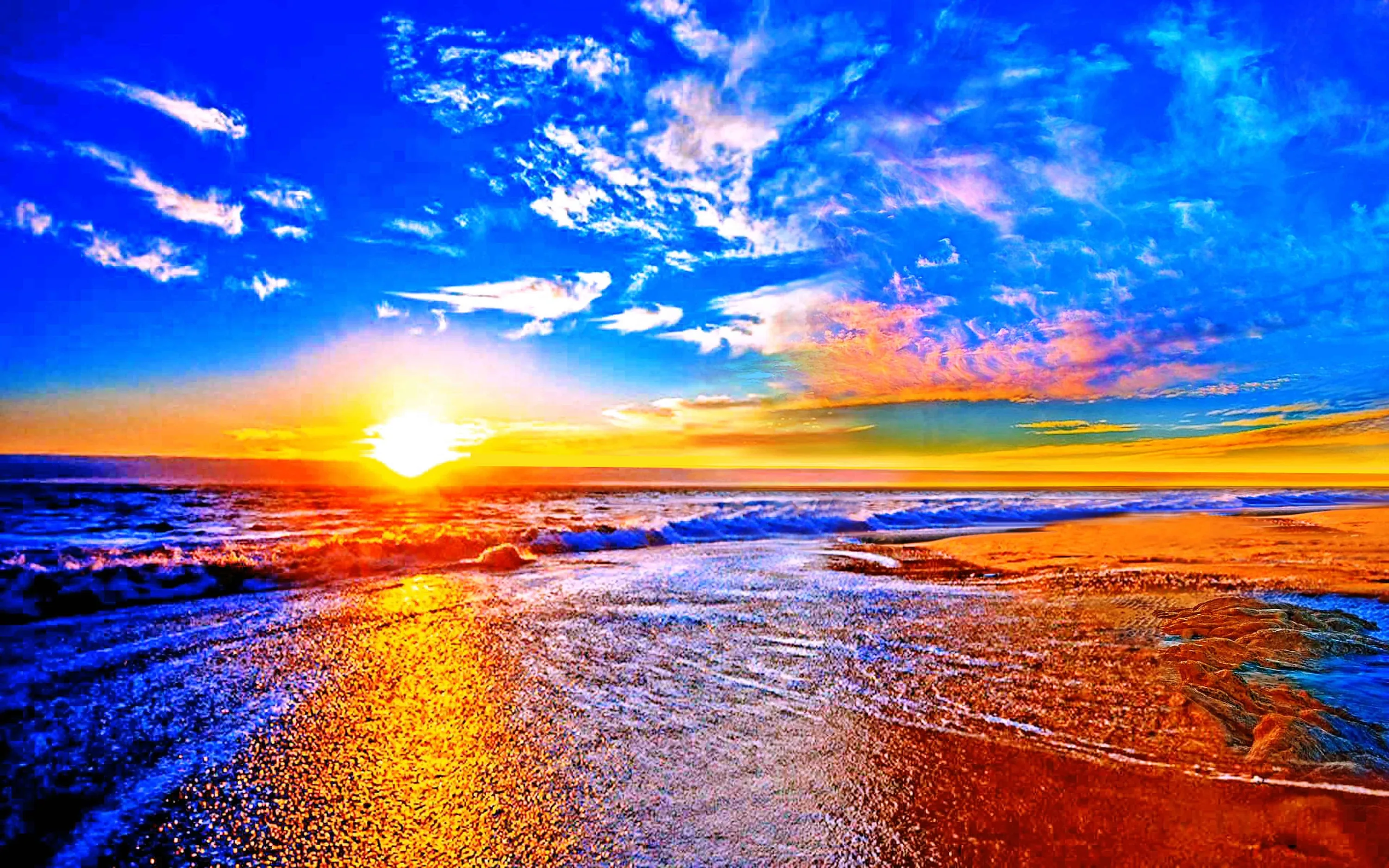 Deeply saturated blue fills most of the sky while the sun flares at the left horizon, wet sand doubling the colours in the lower half.