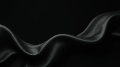Folded silk ripples across the lower half of the frame, the sheen along each crest the only thing lifting it out of the dark.
